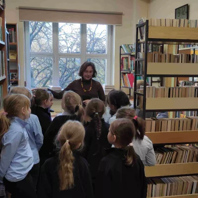 Uczennice klasy 1a SSP słuchają zasad dotyczących korzystania z księgozbioru biblioteki szkolnej omawianych przez nauczyciela bibliotekarza 