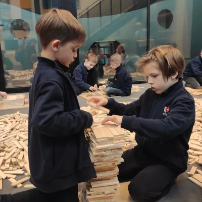 Uczniowie klasy 1b SSP budujący wieżę z drewnianych klocków Linden podczas warsztatów w Monosefera Kreatywności 