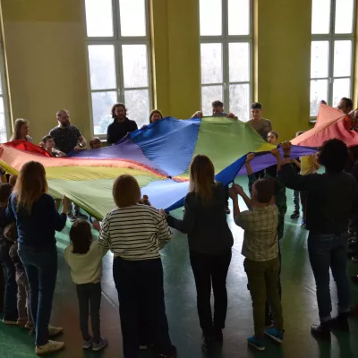 Uczestnicy spotkania w czasie zabawy chustą integracyjną. 