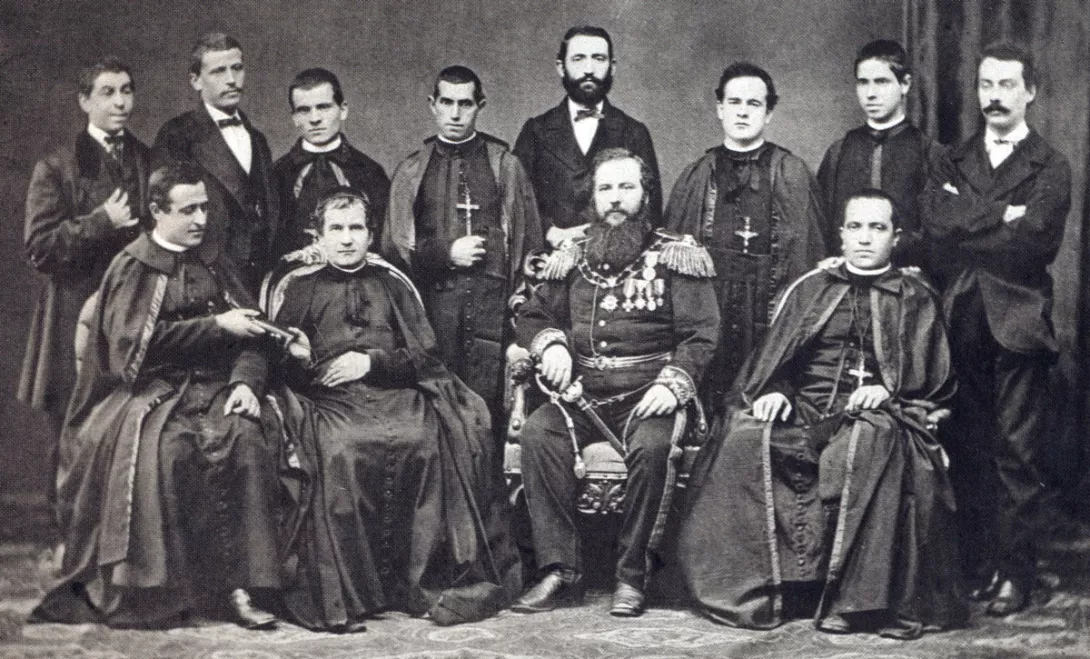 Ksiądz Bosko z pierwszą wyprawą misyjną. Przekazuje tekst konstytucji salezjańskich Janowi Cagliero, który przewodzi wyprawie. Fotografia z 1875 r.