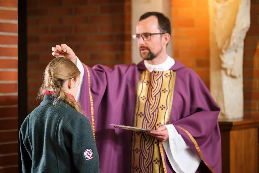 Ks. Piotr Tarabasz posypuje głowy uczniów popiołem. (fot. Amelia Szymańska)