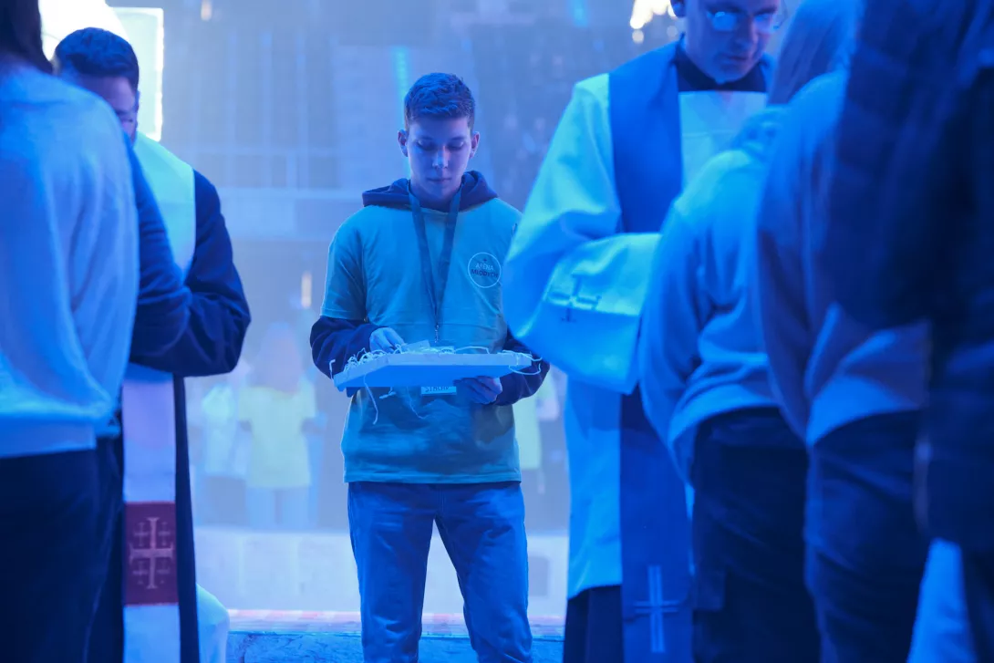 Wolontariusz rozdający karteczkę z ziarnem wprasowanym w papier czerpany.