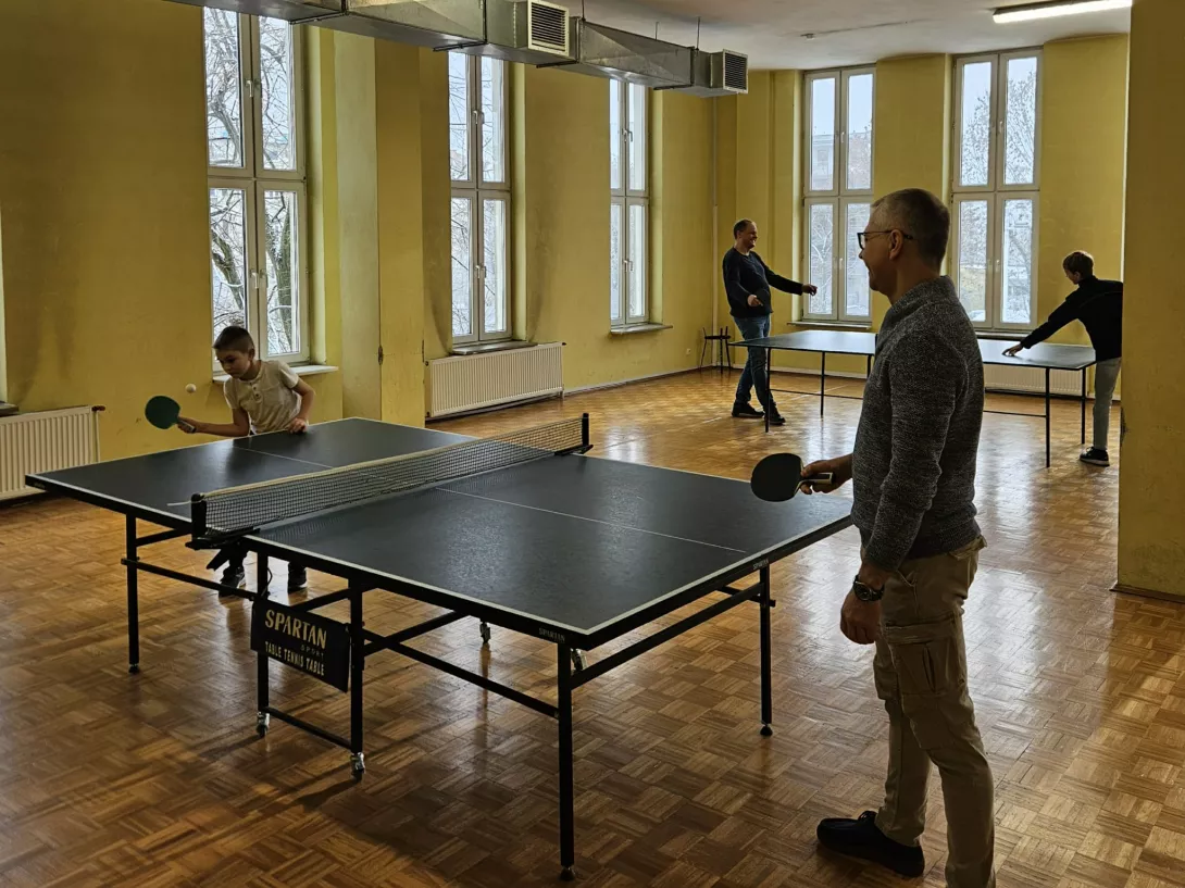 Uczniowie z rodzicami grają w tenisa stołowego