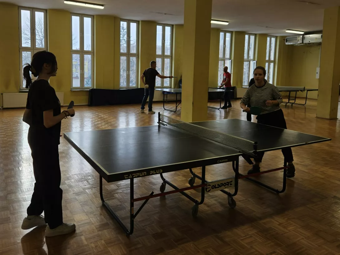 Uczniowie z rodzicami grają w tenisa stołowego