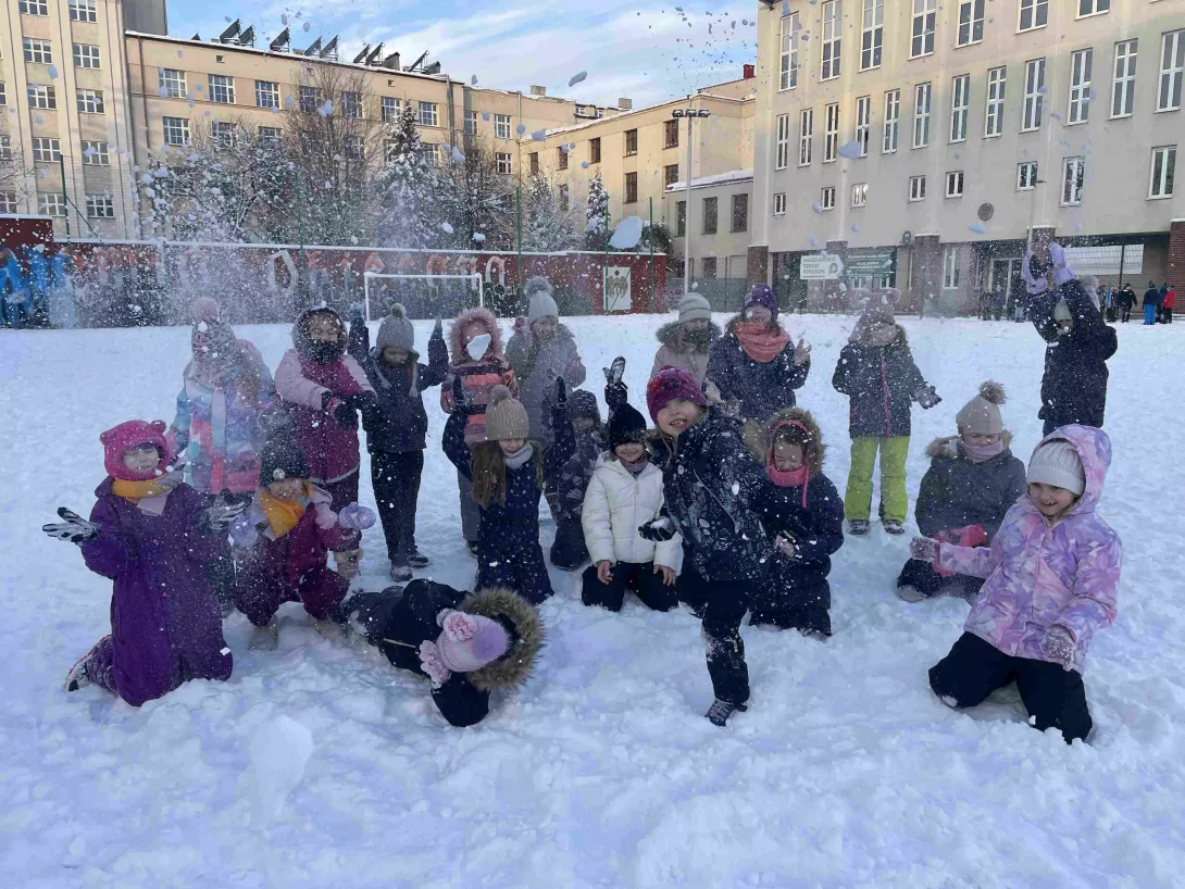 Klasa 1c podczas zabawy na śniegu na szkolnym boisku 