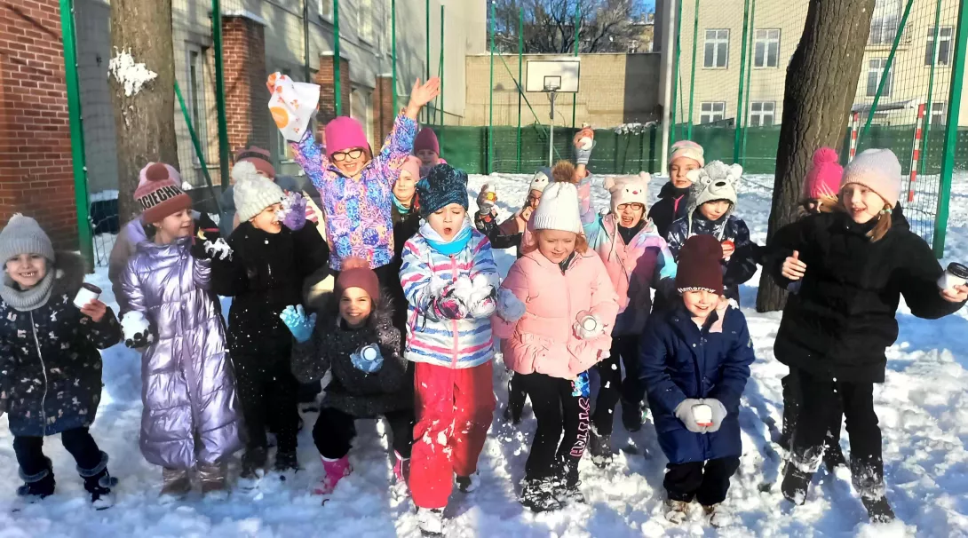 Klasa 2c podczas zabawy na śniegu na szkolnym boisku 