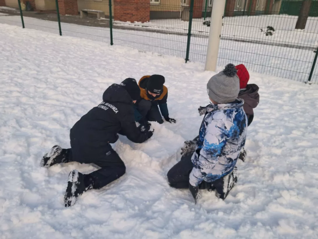 Chłopcy z klasy 3b budujący ze śniegu na szkolnym boisku 