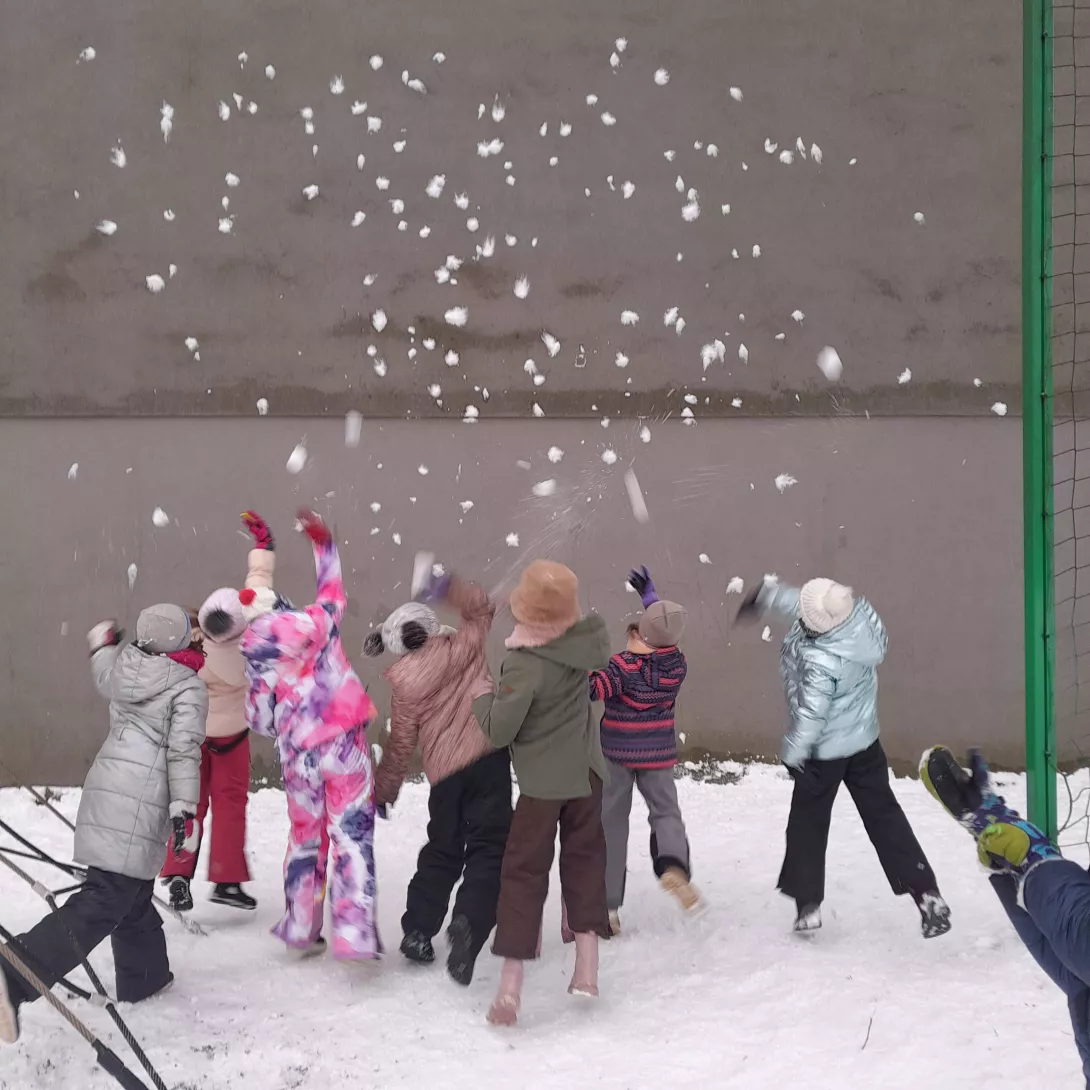 Dziewczyny z klasy 2a rzucające śnieżkami podczas zabawy na boisku szkolnym 