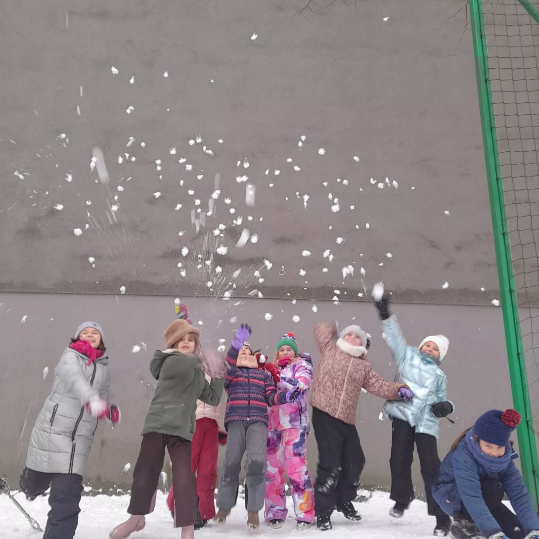 Dziewczyny z klasy 2a rzucające śnieżkami podczas zabawy na boisku szkolnym 