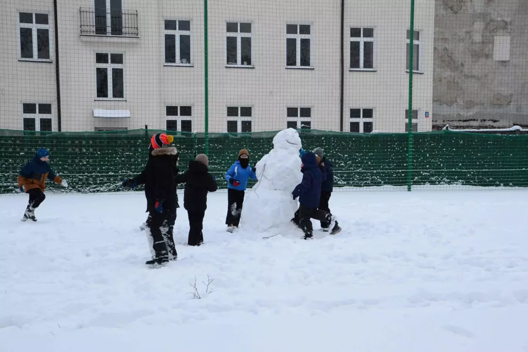 Chłopcy z klasy 2b lepiący bałwana w czasie zabawy na śniegu 