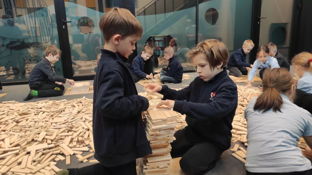 Uczniowie klasy 1b SSP budujący wieżę z drewnianych klocków Linden podczas warsztatów w Monosefera Kreatywności 