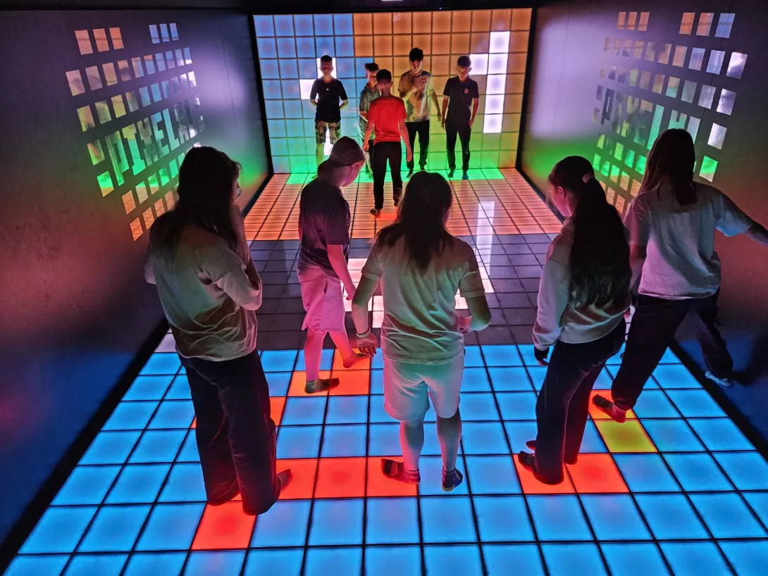 Uczennice i uczniowie skaczą na kolorowej podłodze