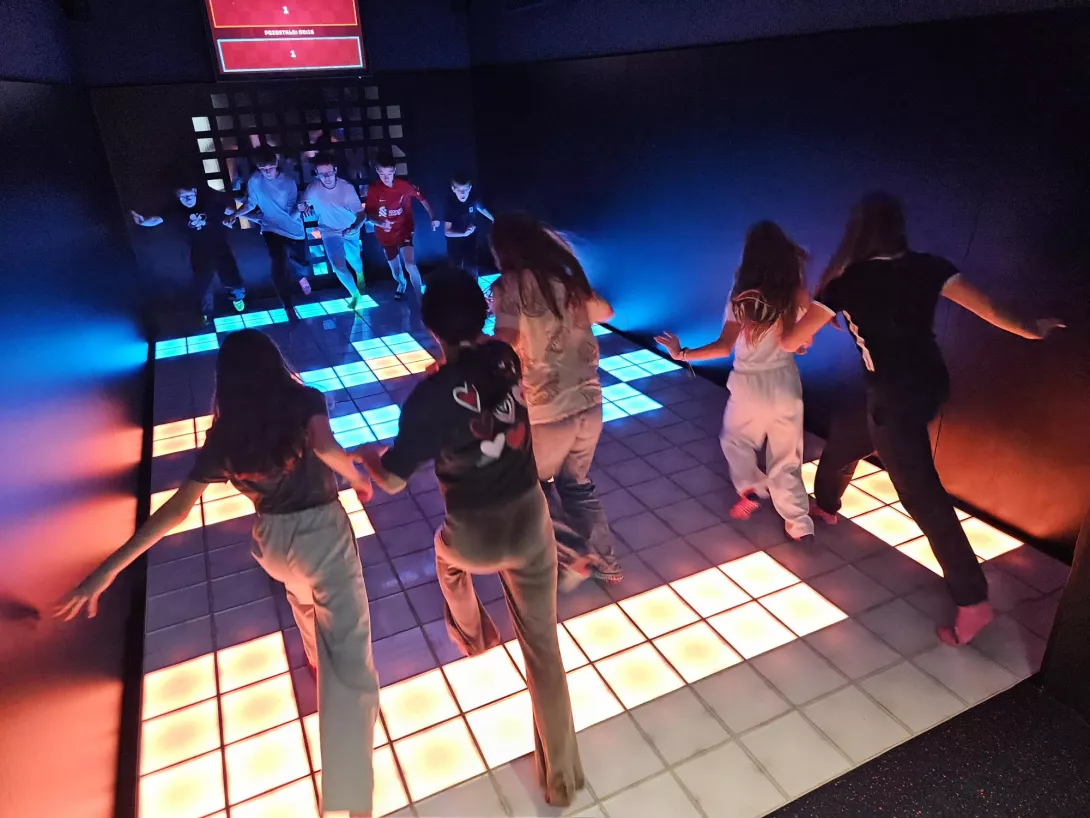 Uczennice i uczniowie skaczą na kolorowej podłodze