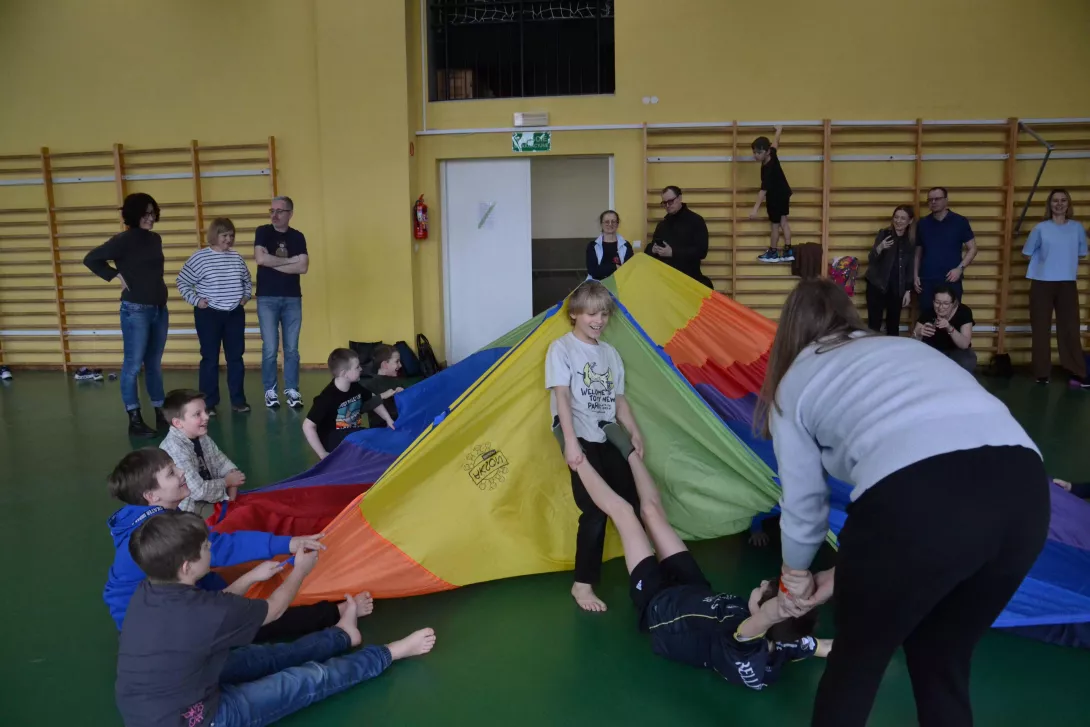 Uczestnicy spotkania w czasie zabawy chustą integracyjną.