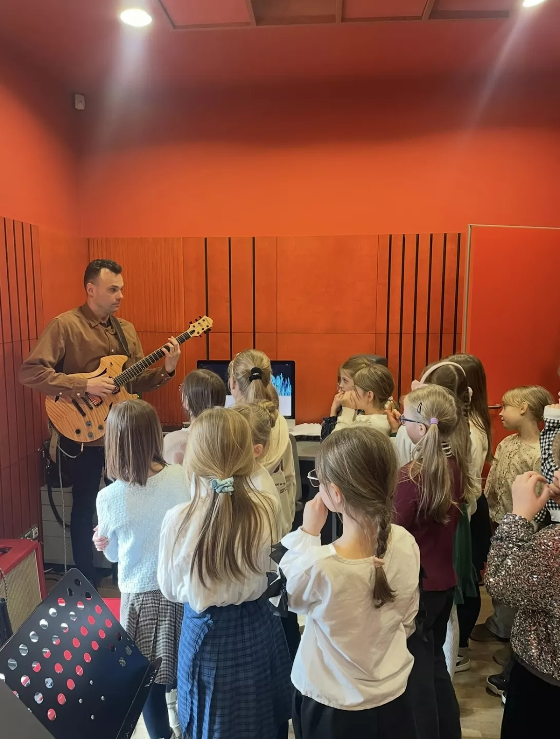 Uczennice słuchają gitary jazzowej.