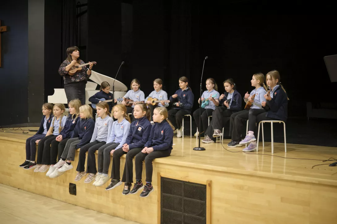 Dzieci wczesnoszkolne grają na ukulele i śpiewają kolędy.